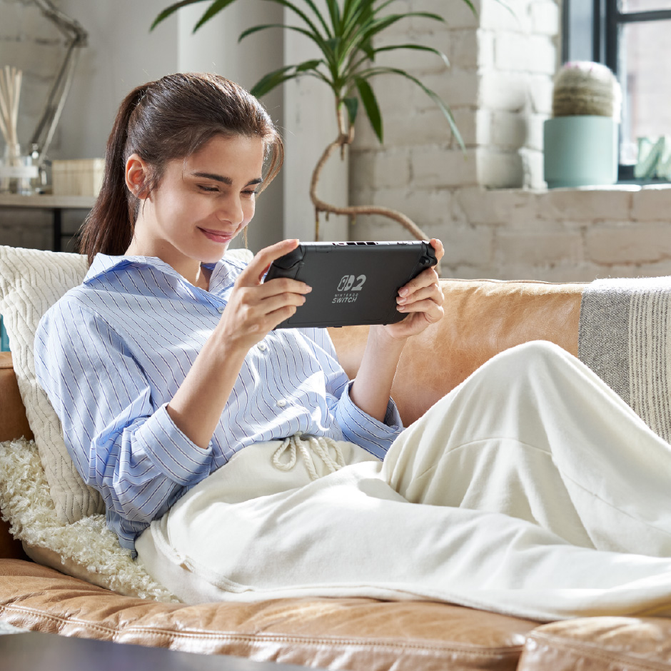 A person sits on a couch holding a Nintendo Switch 2.
